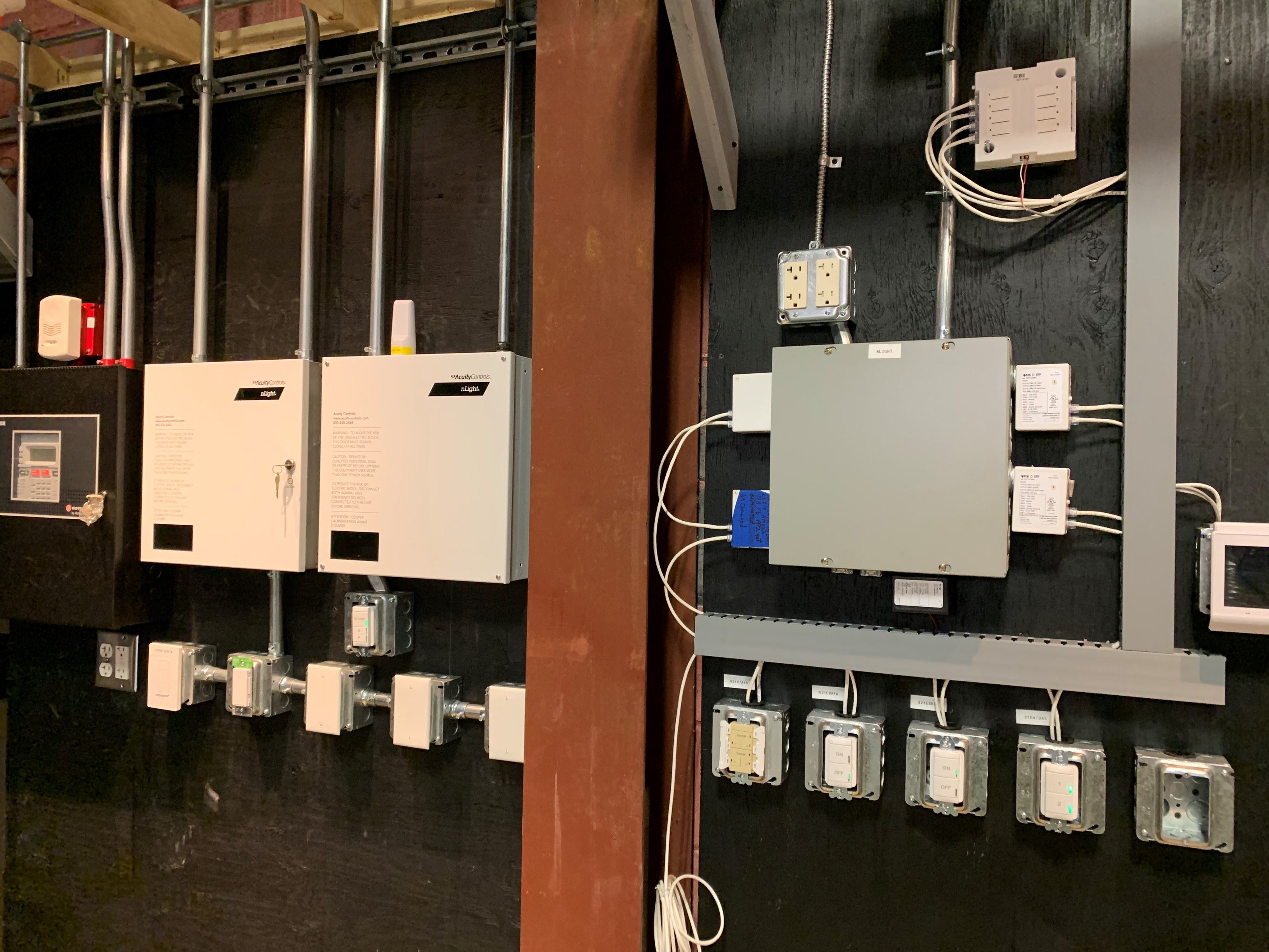 Angle shot of all of Comalli Groups's training apperatuses on the wall of their training center. Wires linking all training pieces together like they would be in a customer's home. 